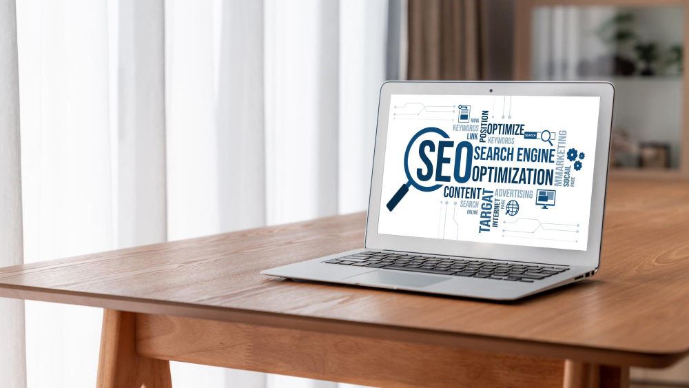 a laptop on top of a table with on-page seo text on screen